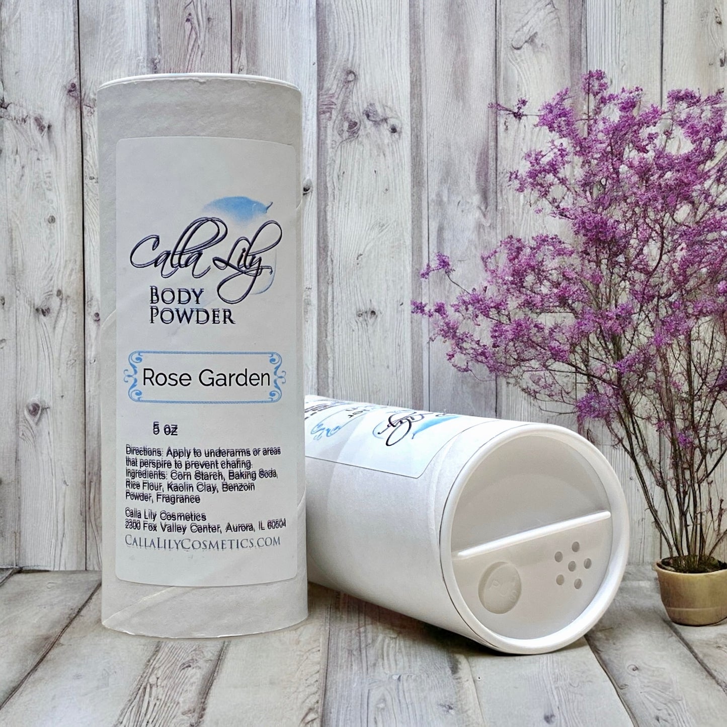 Body powder container with 'Calla Lily' branding on a wooden surface with a plant in the background.