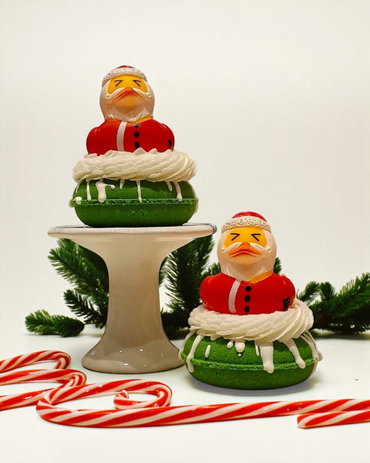 Two green cookies with Santa Claus figures on top, surrounded by candy canes and Christmas decorations.