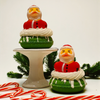Two green cookies with Santa Claus figures on top, surrounded by candy canes and Christmas decorations.