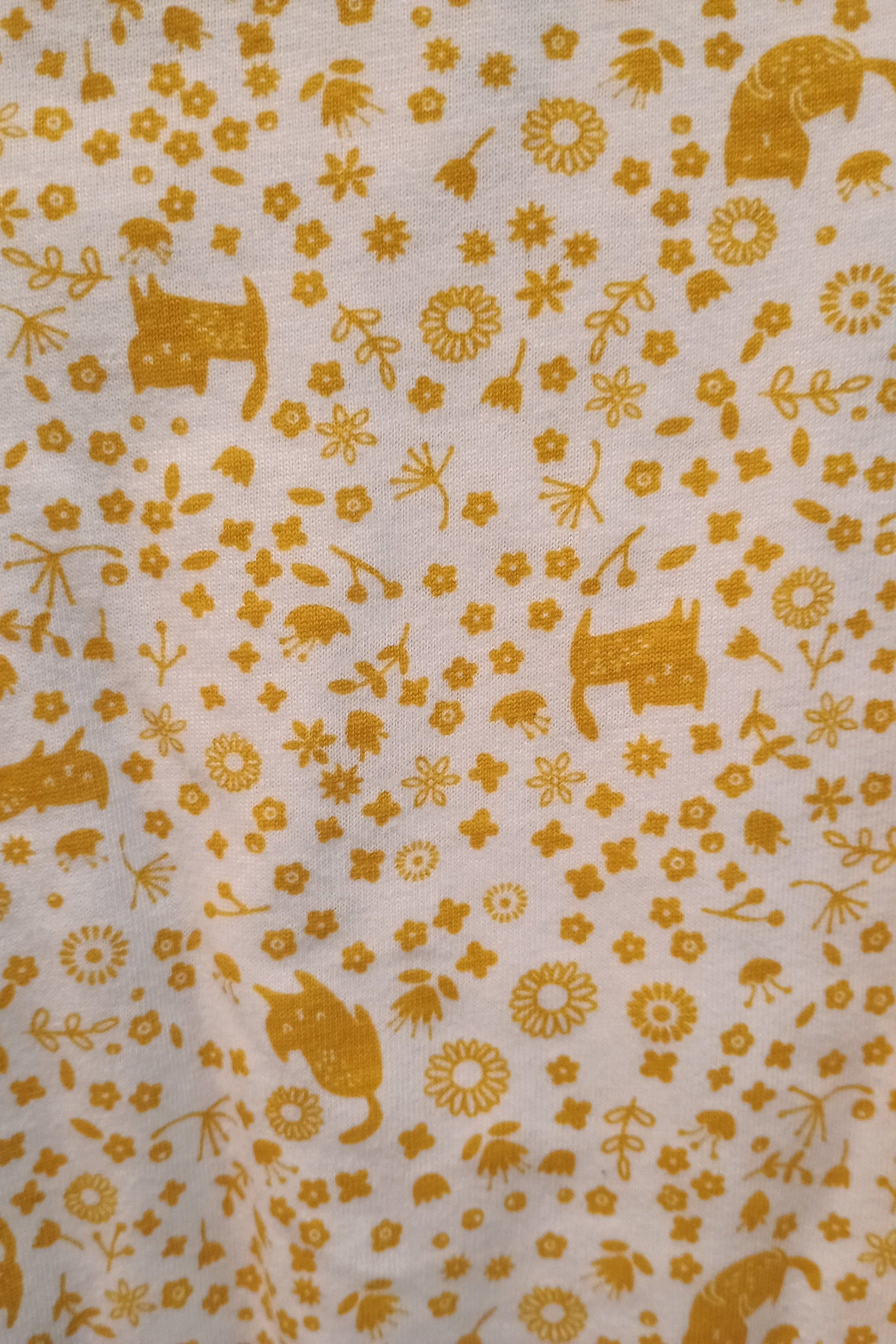 Patterned fabric with yellow animals and flowers on a white background