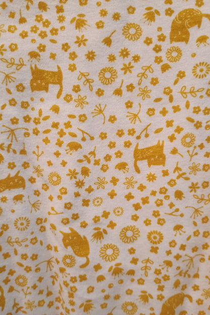 Patterned fabric with yellow animals and flowers on a white background