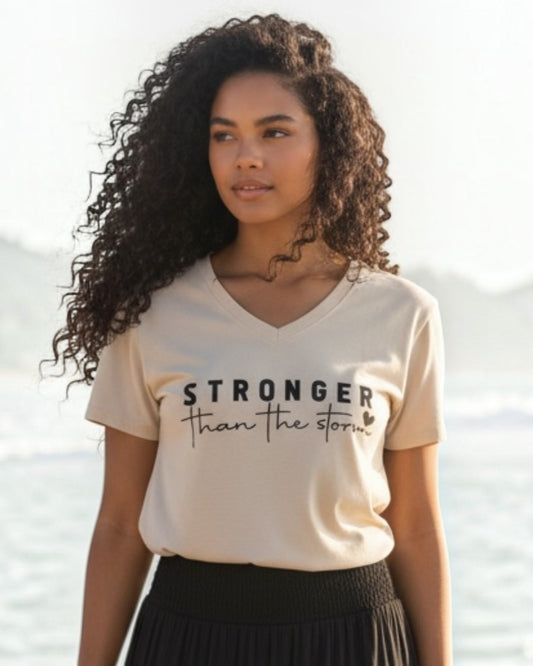 Woman standing on a beach wearing a beige t-shirt with text and a black skirt.