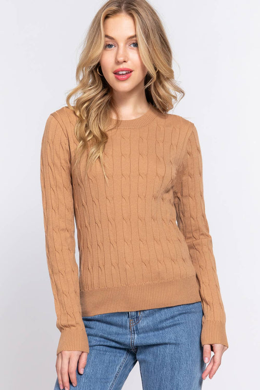 Woman wearing a brown cable knit sweater and blue jeans on a white background