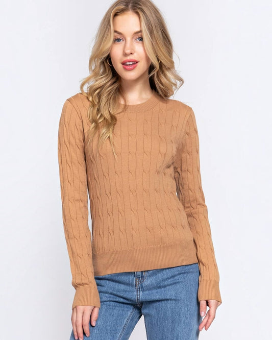 Woman wearing a brown cable knit sweater and blue jeans on a white background