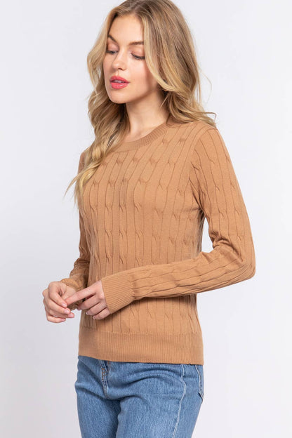 Woman wearing a brown cable knit sweater and blue jeans on a white background
