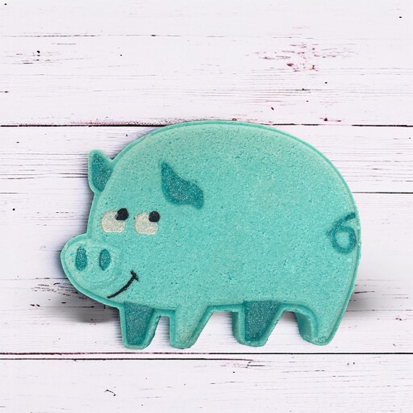 Teal pig-shaped bath toy on a white wooden background