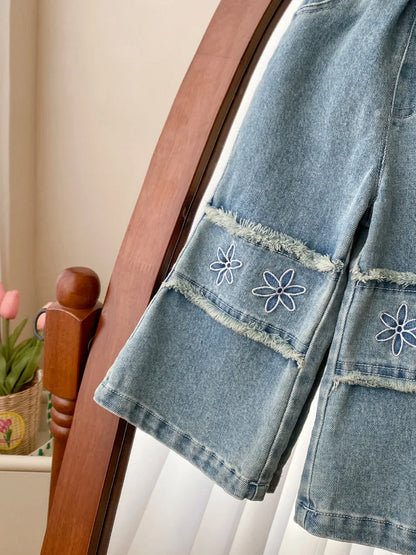 Denim pants with floral embroidery on a wooden chair