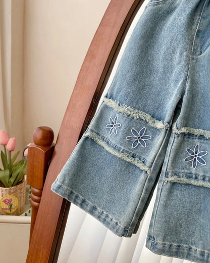 Denim pants with floral embroidery on a wooden chair