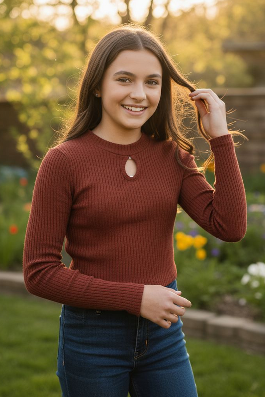 Woman in a red sweater standing in a garden with flowers and greenery.