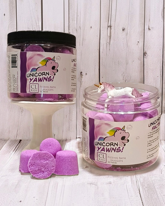 Jar of purple bath fizzies labeled 'Unicorn Yawns' on a wooden surface.
