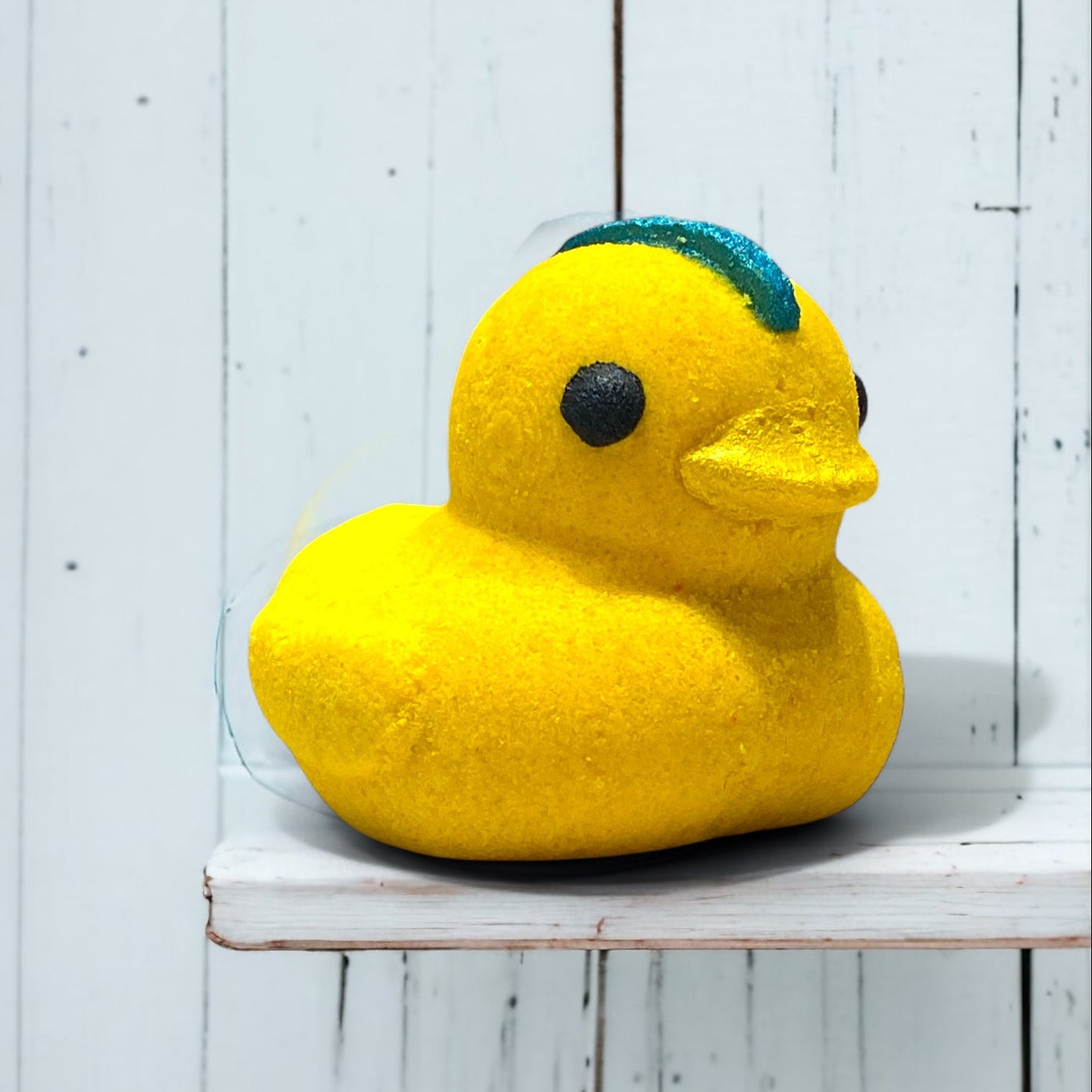 Yellow rubber duck with a blue mohawk on a white wooden shelf
