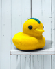 Yellow rubber duck with a blue mohawk on a white wooden shelf