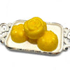 Three yellow mooncakes on a decorative silver tray with a white background