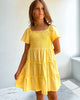 Young girl wearing a yellow dress against a white wall.