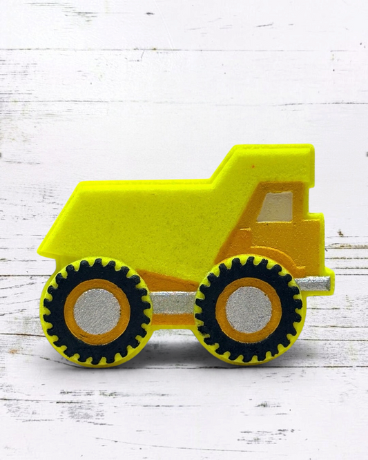 Yellow bath bomb dump truck on a white wooden surface