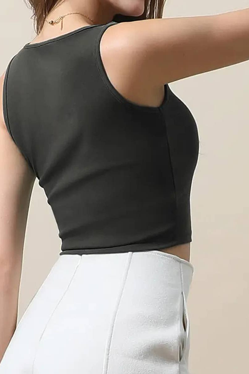 Person wearing a black sleeveless top and white pants on a beige background