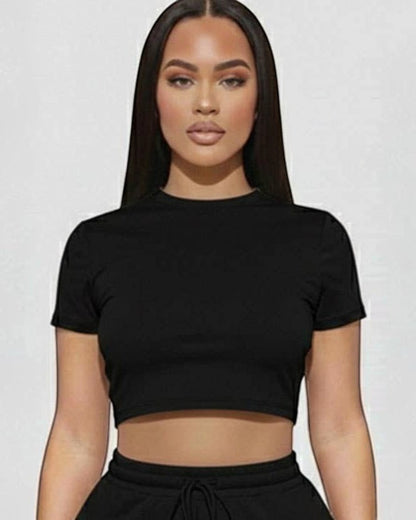 Woman wearing a black crop top and shorts set on a white background