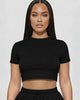 Woman wearing a black crop top and shorts set on a white background