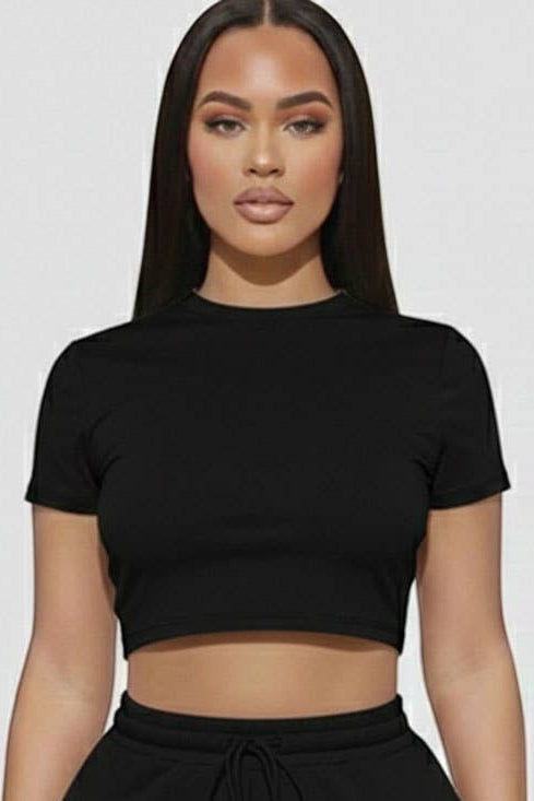 Woman wearing a black crop top and shorts set on a white background