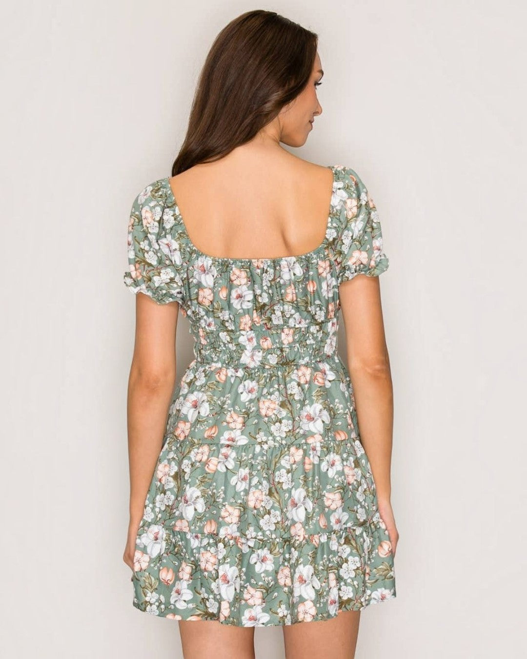 Woman wearing a floral dress against a plain background