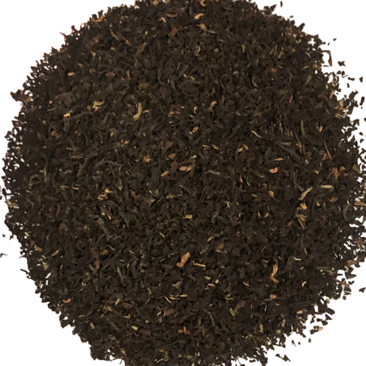A pile of dark, finely ground loose-leaf tea or herbal blend filling a light-colored container.