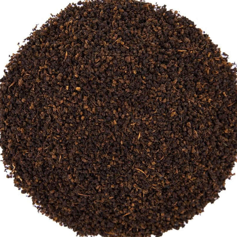 A circular pile of dark brown coffee grounds or tea leaves on a solid white background.