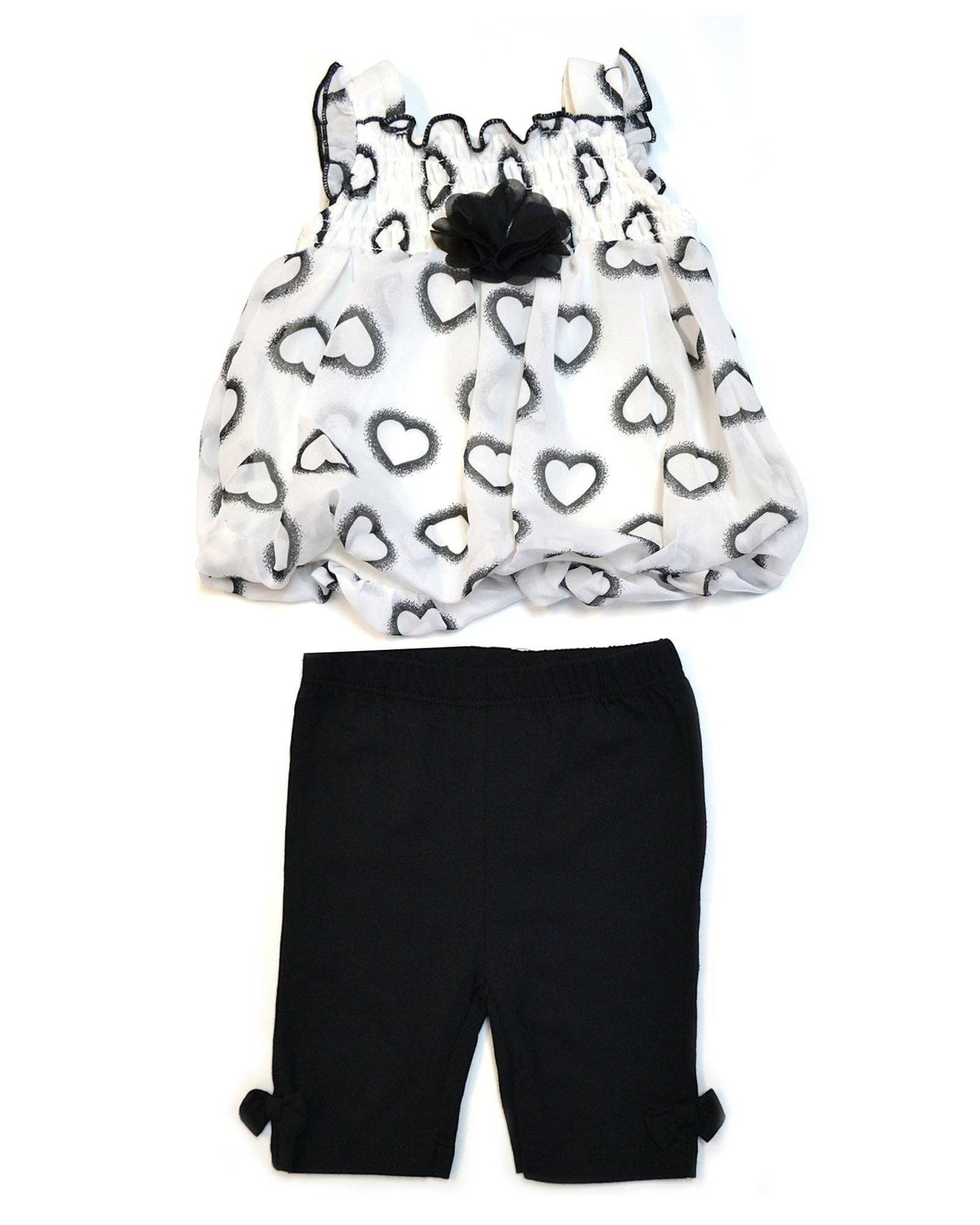 Children's outfit with heart-patterned top and black shorts on a white background
