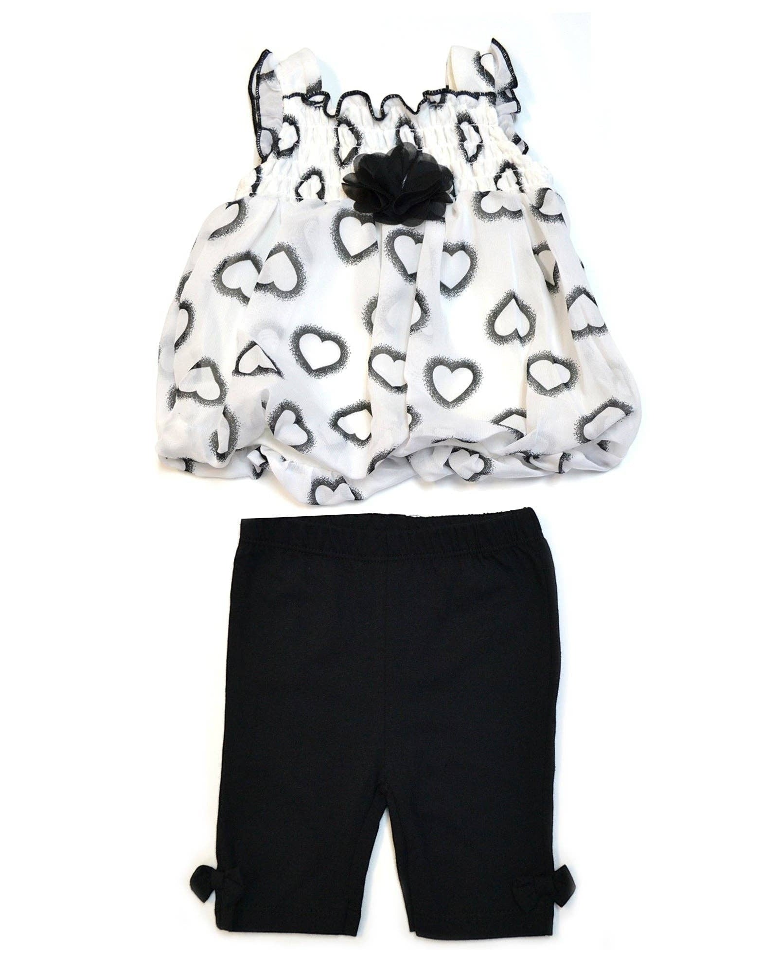 Children's outfit with heart-patterned top and black shorts on a white background