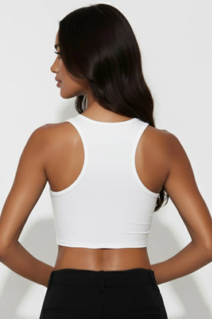 Woman wearing a white crop top and black pants on a plain background