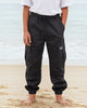 Person wearing a white shirt and black pants standing on a beach.