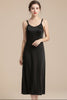 Black slip dress on a hanger against a white background