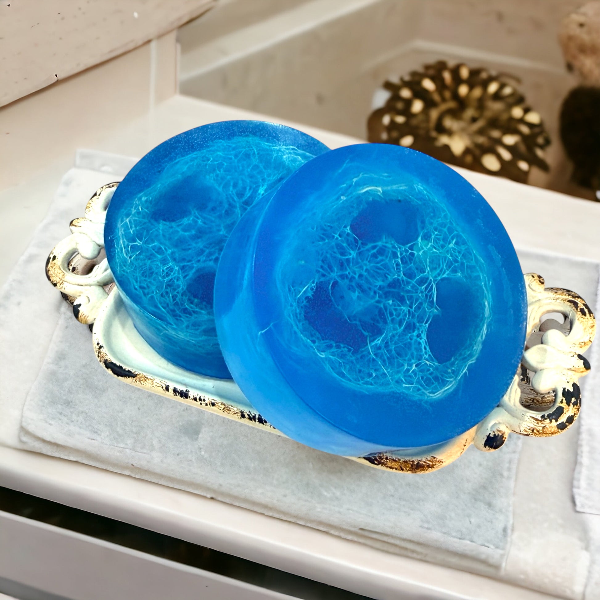 Two blue soap bars on a decorative tray with a mirror in the background