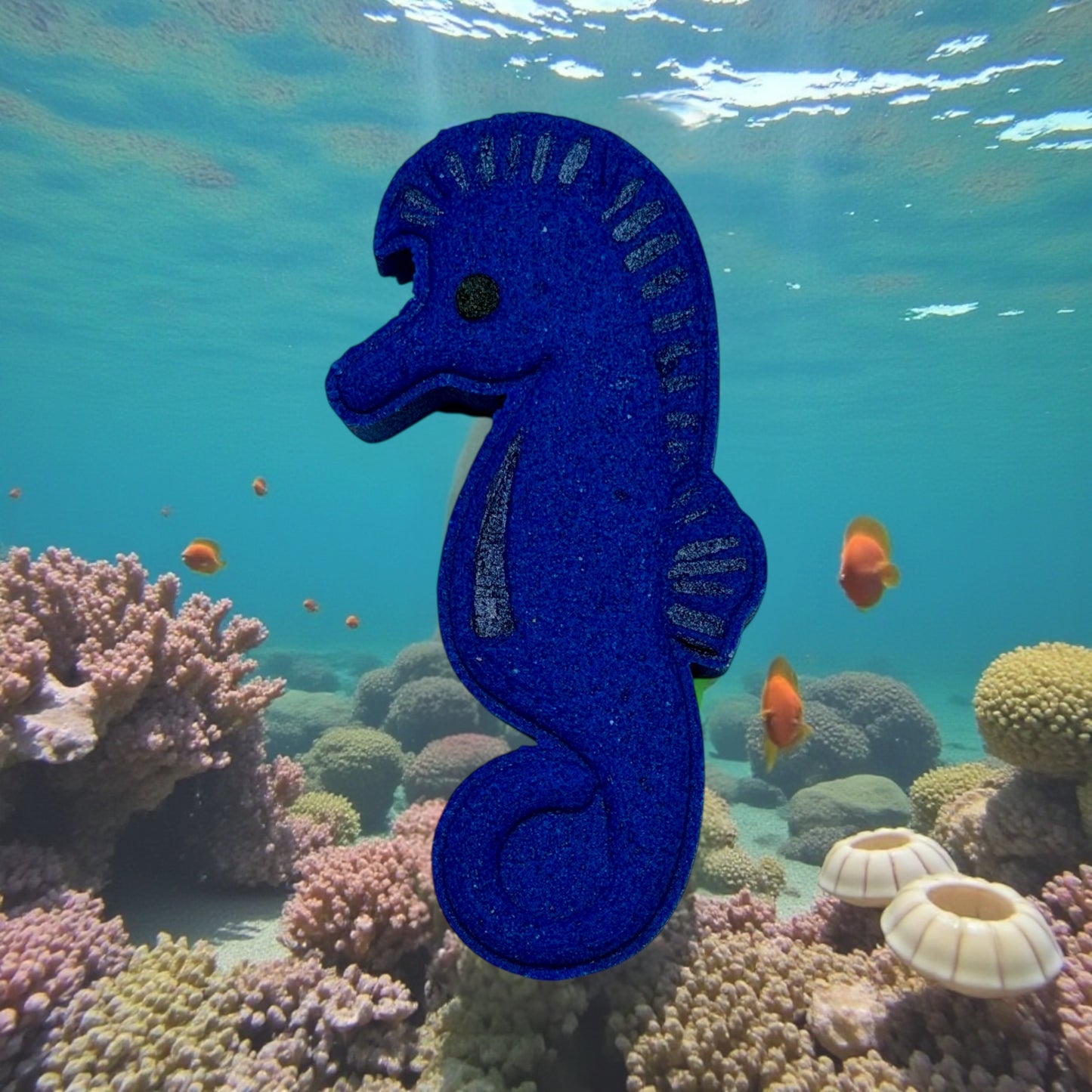 Blue seahorse bath bomb in an underwater scene with coral and fish