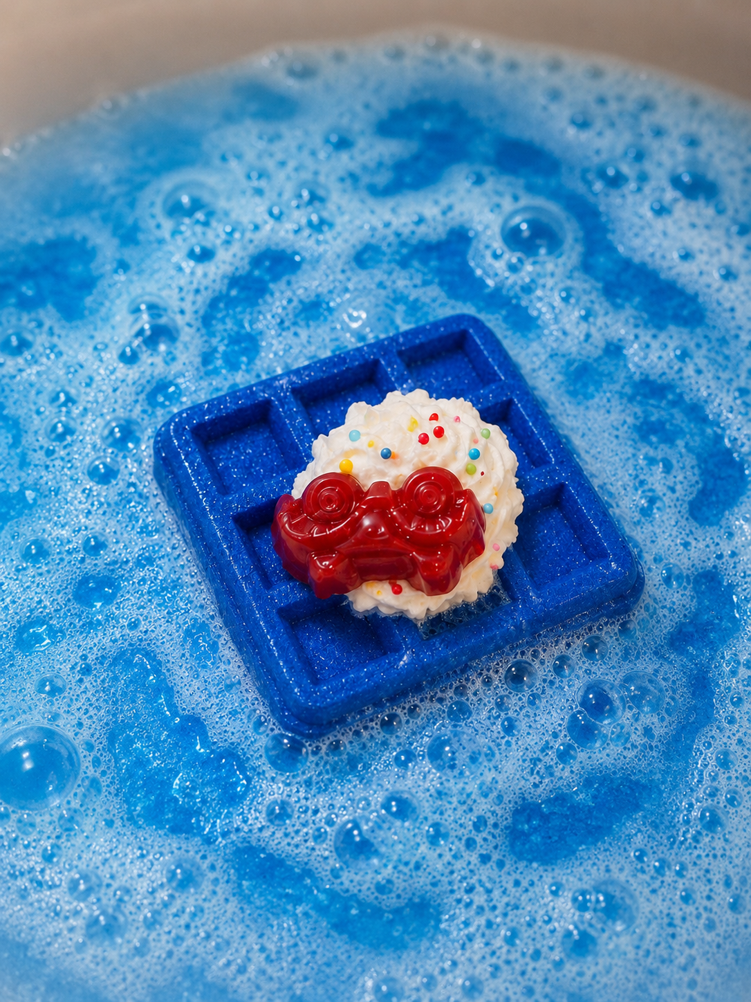 Blue waffle mold with a dessert on a blue bubbly surface