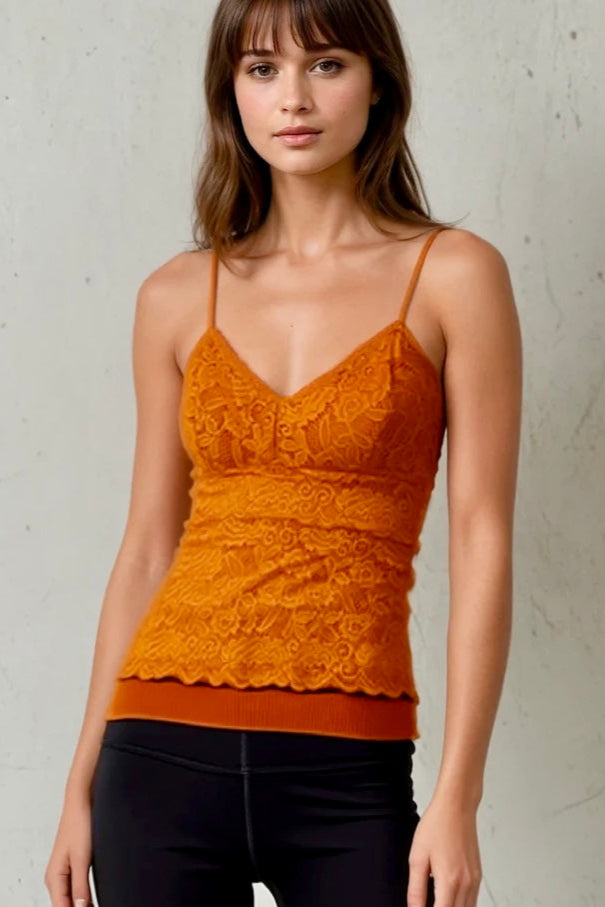 Woman wearing an orange lace top against a plain background