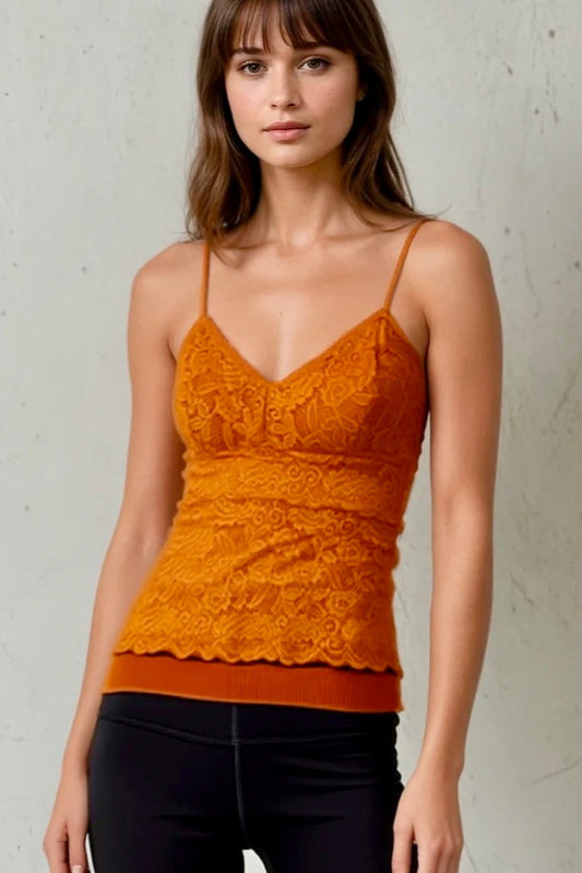 Woman wearing an orange lace top against a plain background