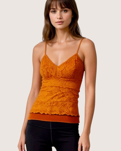 Woman wearing an orange lace top against a plain background