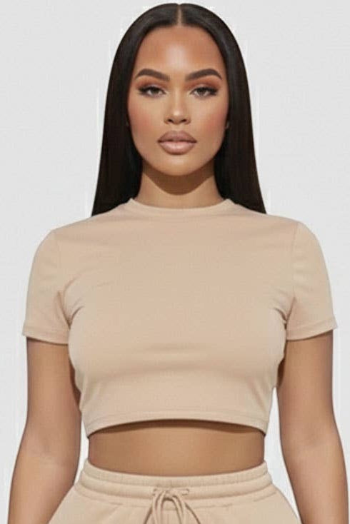 Woman wearing a beige crop top and shorts set on a white background