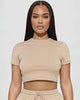 Woman wearing a beige crop top and shorts set on a white background
