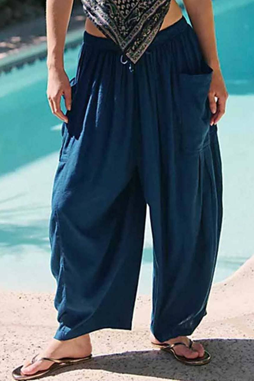 Person wearing blue harem pants by a pool