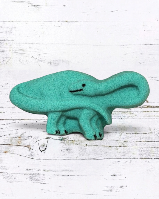 Calla Lily Cosmetics + CL kids teal brontosaurus shaped bath bomb with floral scent on a white wooden background