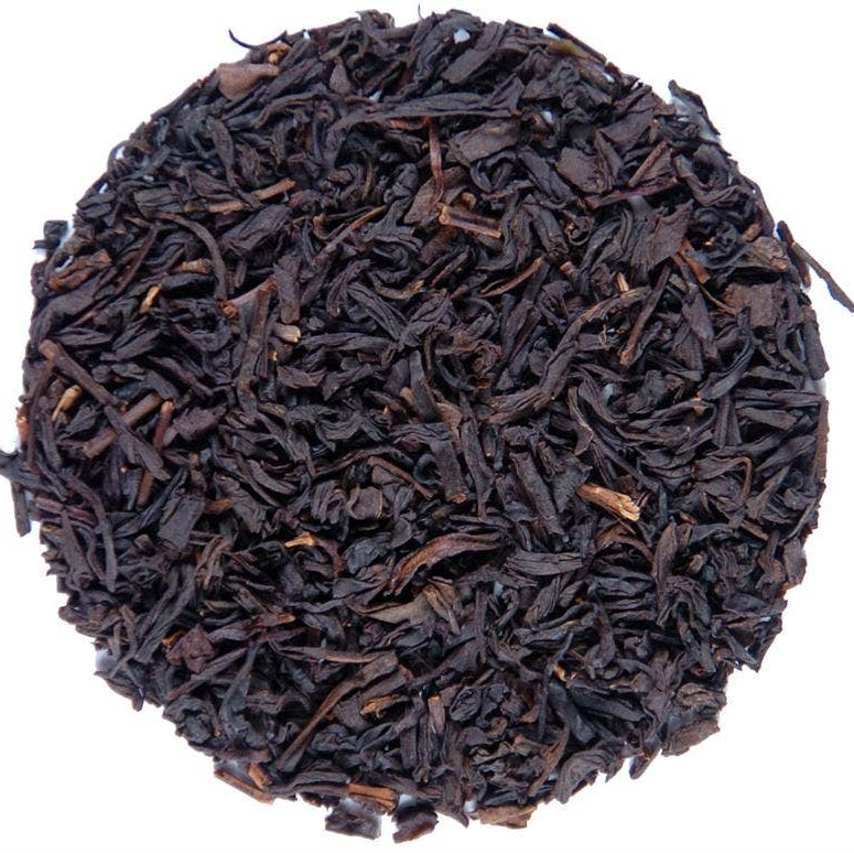 A circular pile of dark brown to black loose-leaf tea leaves on a plain white background.