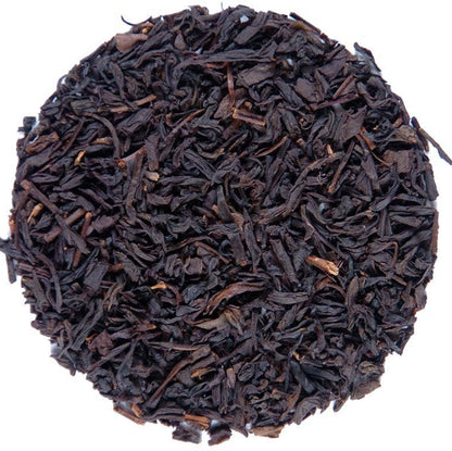 A circular pile of dark brown to black loose-leaf tea leaves on a plain white background.