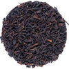 A circular pile of dark brown to black loose-leaf tea leaves on a plain white background.