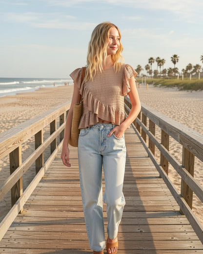 Calla Lily Cosmetics + CL kids girl's beige textured asymmetrical sleeveless top with ruffle detail on a beach pier.