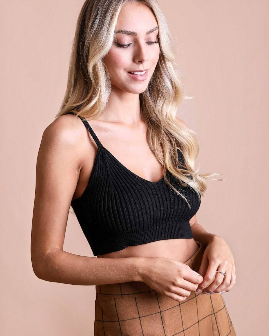 Model wearing a black Calla Lily Cosmetics + CL kids ribbed knit brami crop top with a V-neckline.