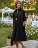 Woman wearing a black Calla Lily Cosmetics + CL kids long sleeve polyester shirt dress at an outdoor garden event.