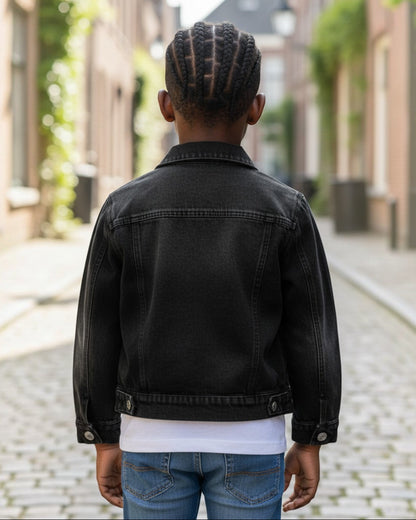 Toddler wearing a black acid wash denim jacket by Calla Lily Cosmetics + CL kids on a cobblestone street.