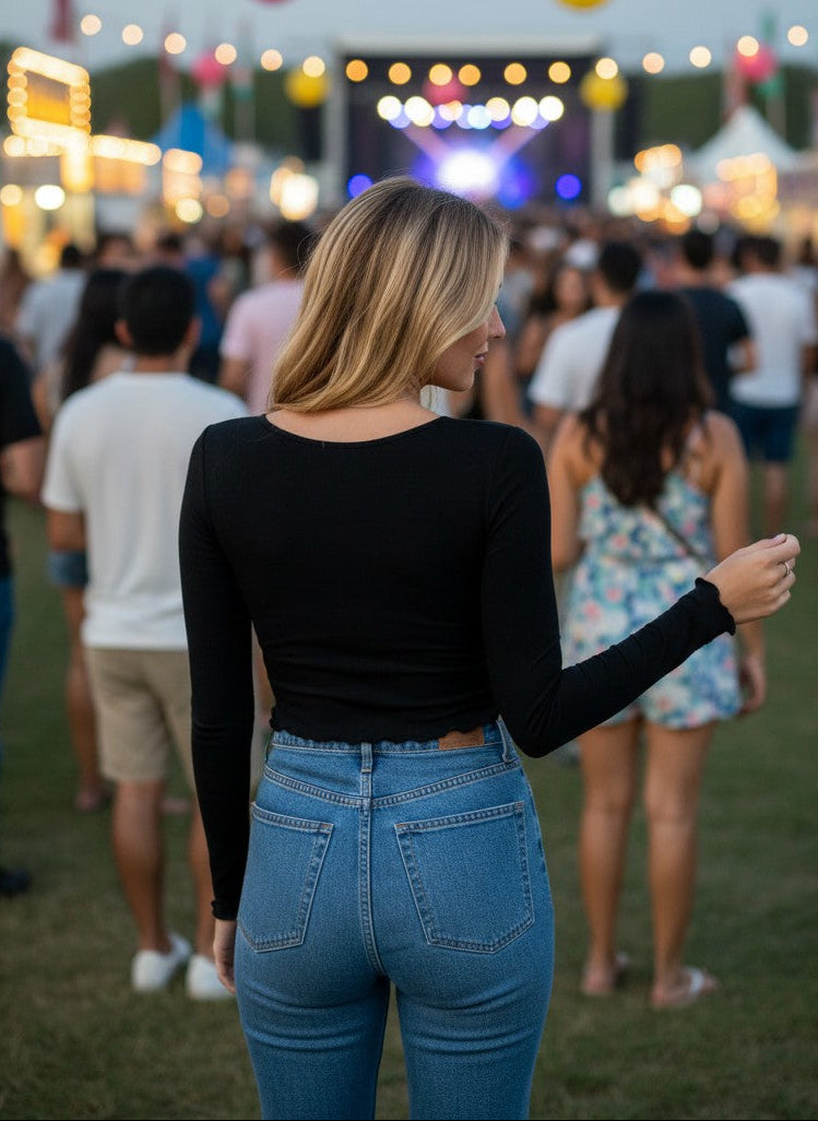 Woman wearing Calla Lily Cosmetics + CL kids black long sleeve twisted knit top with blue jeans at a music festival.