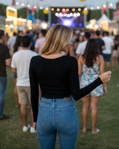 Woman wearing Calla Lily Cosmetics + CL kids black long sleeve twisted knit top with blue jeans at a music festival.